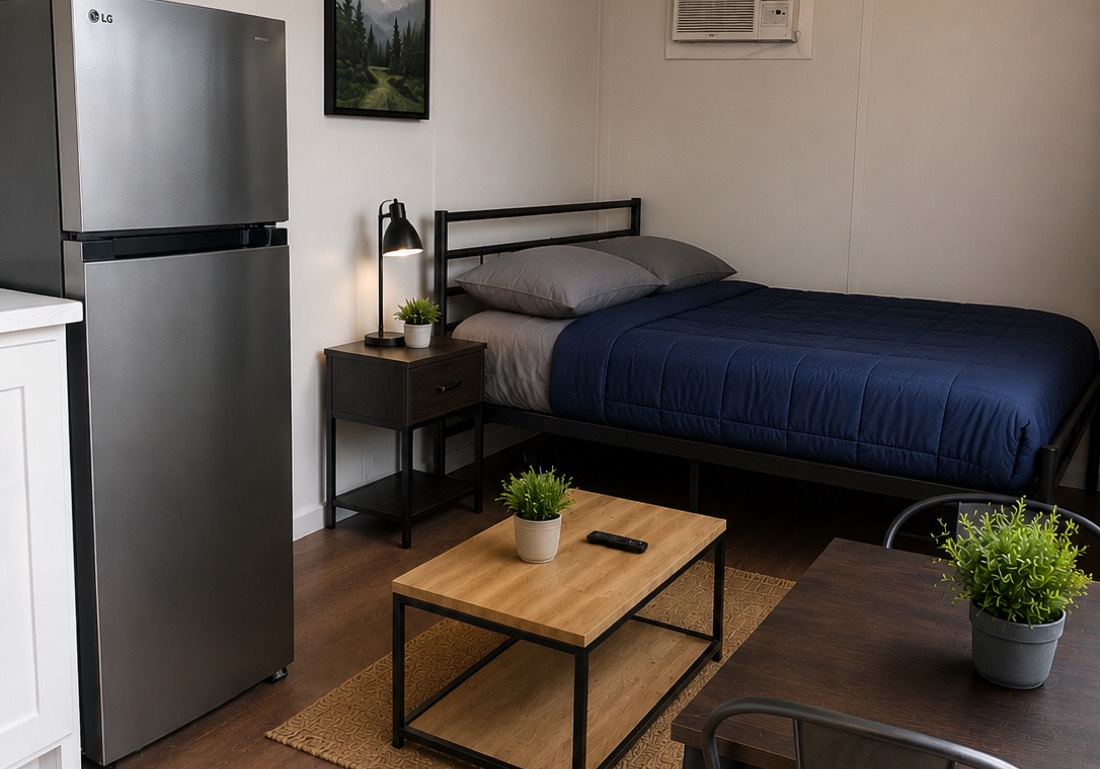 Studio interior — bed, full-size fridge, A/C